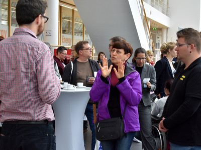 Viele Menschen auf der Auftaktveranstaltung. Im Vordergrund eine Gebärdensprechende Frau.